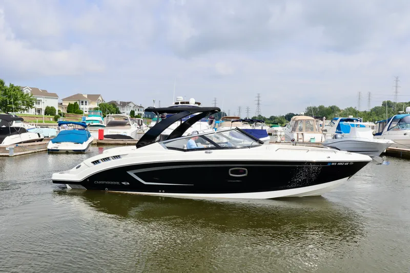 Slide: The Image of 2016 Chaparral 307 SSX boat docked in a marina, surrounded by other boats. - 15
