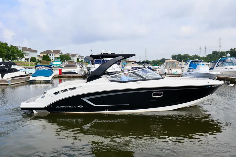 Slide: The Image of 2016 Chaparral 307 SSX boat docked in a marina, surrounded by other boats. - 24