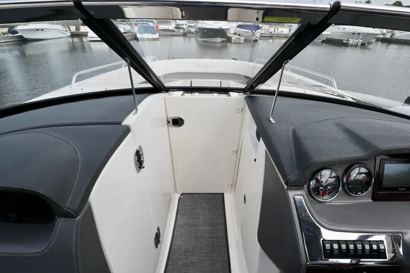 Slide: The Image of 2016 Chaparral 307 SSX boat interior with dashboard and open windshield at marina. - 28