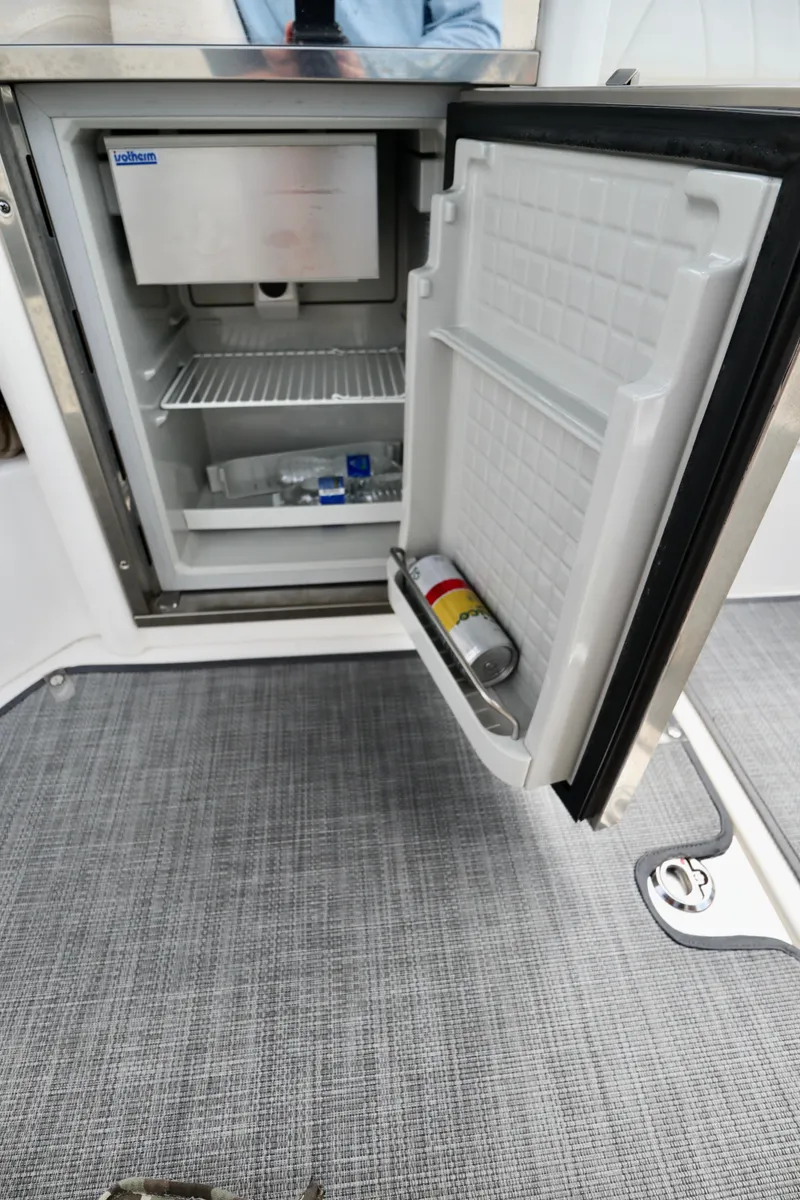 Slide: The Image of Open mini fridge on 2016 Chaparral 307 SSX boat, showing interior storage and contents. - 31