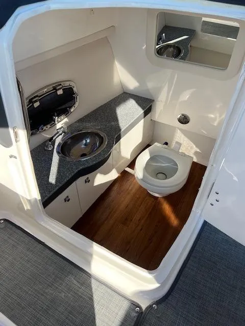 Slide: The Image of 2016 Chaparral 307 SSX boat bathroom with sink, toilet, and wood flooring. - 45