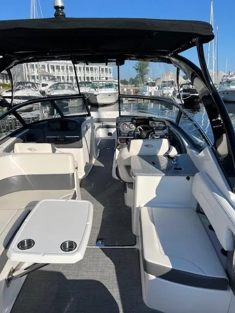 Slide: The Image of 2016 Chaparral 307 SSX boat interior with seating, table, and helm, docked at marina. - 49
