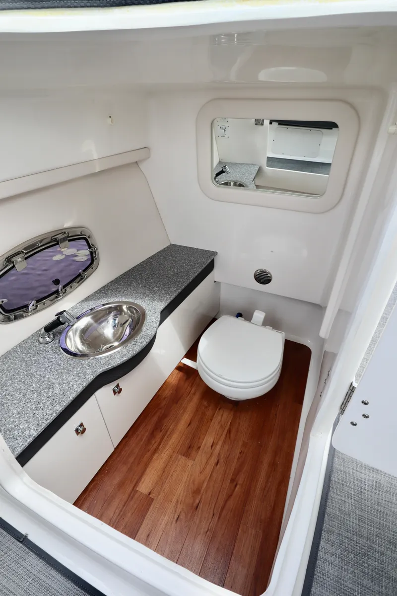 Slide: The Image of 2016 Chaparral 307 SSX boat interior with sink, toilet, and wood flooring. - 7