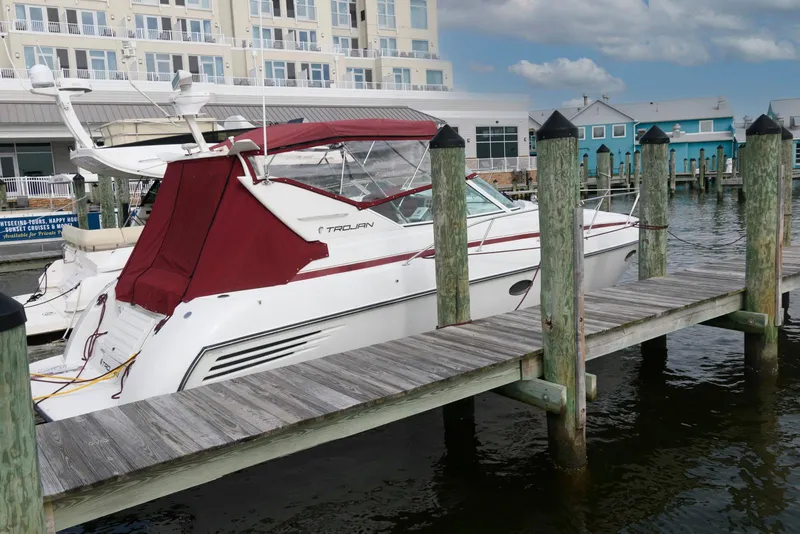 Slide: The Image of 1996 Trojan 350 Express yacht docked at marina with red canopy and waterfront buildings. - 2