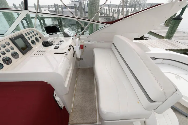 Slide: The Image of 1996 Trojan 350 Express boat cockpit with white seating and control panel by the dock. - 6