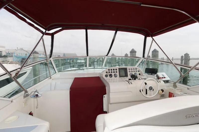 Slide: The Image of 1996 Trojan 350 Express boat cockpit with red canopy and marina view. - 7