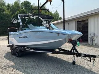 Slide: The Image of 2023 MasterCraft NXT22 boat on trailer, parked outdoors near a building. - 3