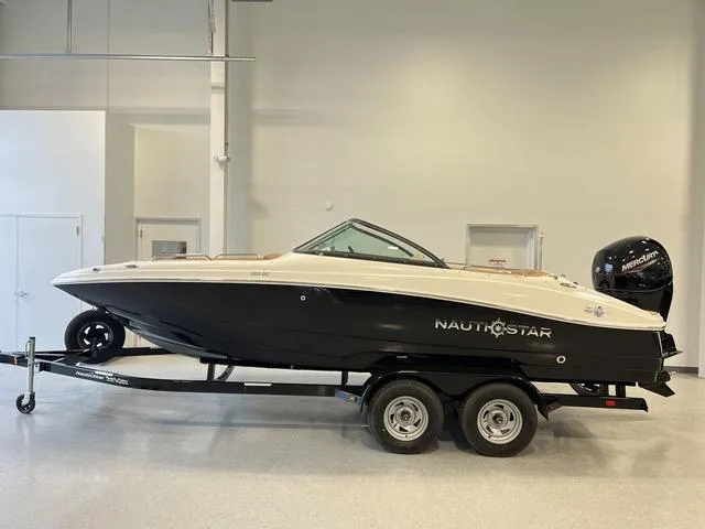 Slide: The Image of 2024 NauticStar 203 DC boat on trailer in indoor showroom. - 1