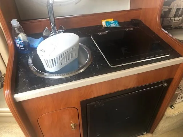 Slide: The Image of 2003 Rinker Fiesta Vee 270 boat kitchenette with sink, stove, and mini-fridge. - 10
