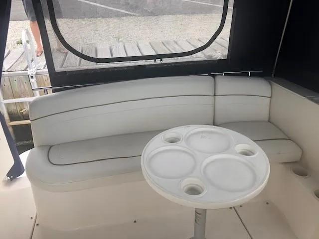 Slide: The Image of 2003 Rinker Fiesta Vee 270 boat interior with white seating and round table. - 6