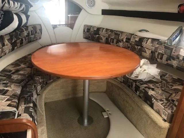 Slide: The Image of 2003 Rinker Fiesta Vee 270 cabin interior with round wooden table and patterned seating. - 7