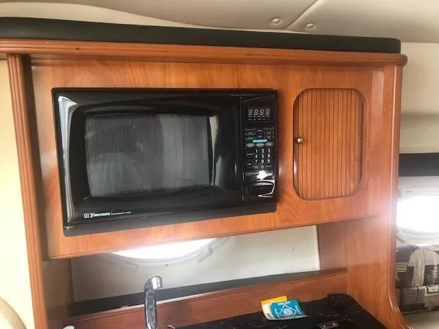 Slide: The Image of 2003 Rinker Fiesta Vee 270 boat interior with microwave and wooden cabinetry. - 9