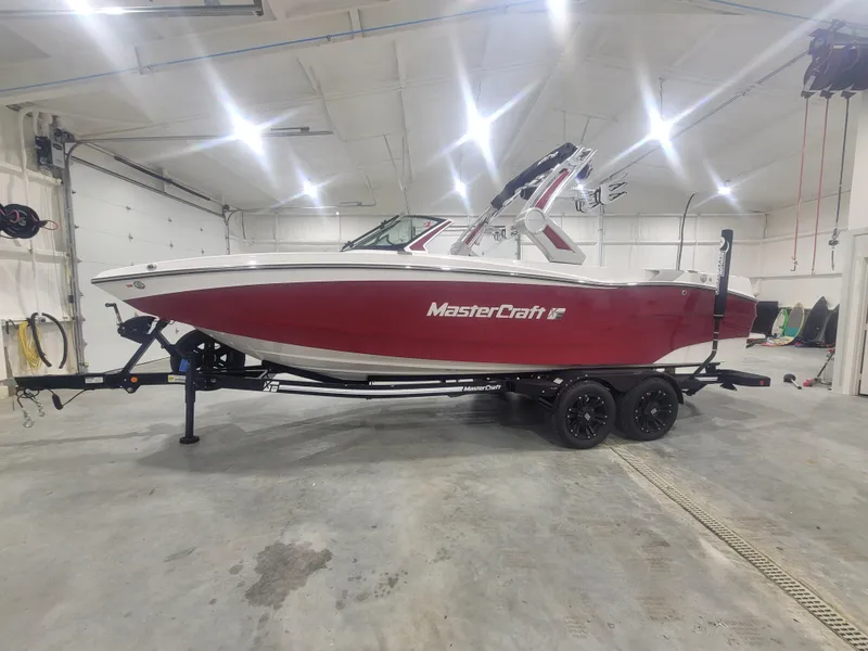 Slide: The Image of 2024 MasterCraft XT24 boat in a garage, red and white exterior. - 1
