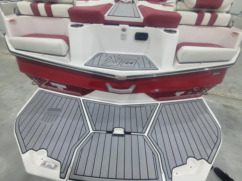 Slide: The Image of 2024 MasterCraft XT24 boat rear view with red and white seating and grey deck. - 18