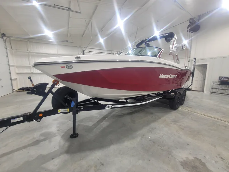 Slide: The Image of 2024 MasterCraft XT24 boat in a showroom, red and white exterior. - 2