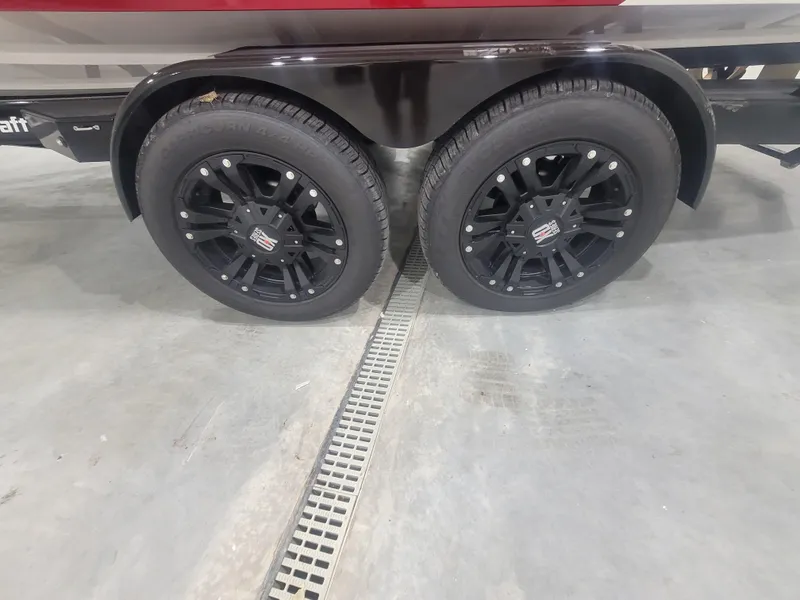Slide: The Image of 2024 MasterCraft XT24 trailer with black alloy wheels in a showroom. - 24