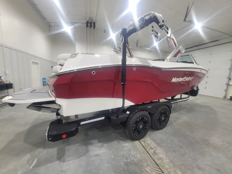 Slide: The Image of 2024 MasterCraft XT24 boat in a showroom, red and white exterior, on a black trailer. - 6