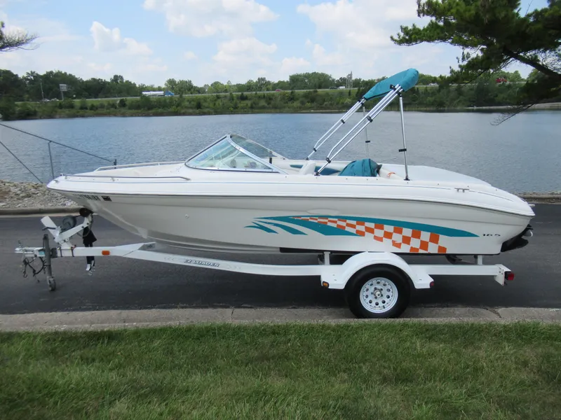Slide: The Image of 1997 Sea Ray 185 Bow Rider boat on trailer by a lake. - 10