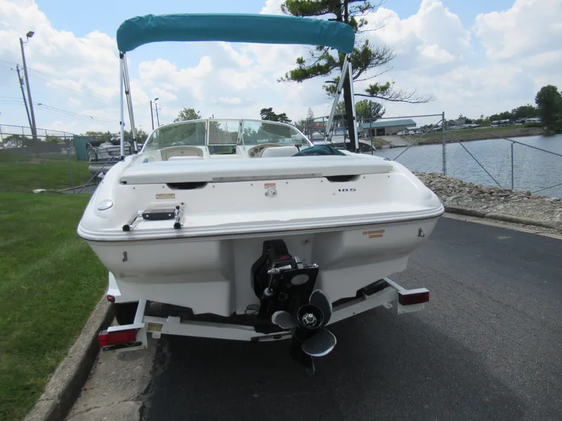 Slide: The Image of 1997 Sea Ray 185 Bow Rider boat with teal canopy, parked near a lake. - 2