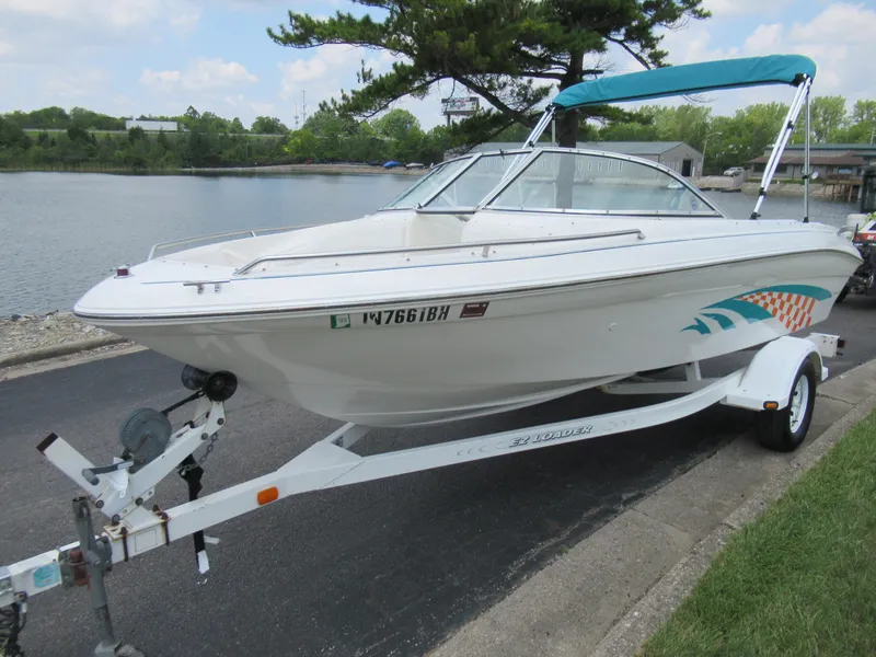 Slide: The Image of 1997 Sea Ray 185 Bow Rider boat on trailer by a lake. - 9