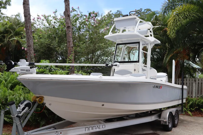 Slide: The Image of 2021 Robalo 246 Cayman SD boat on a trailer in a tropical setting. - 2