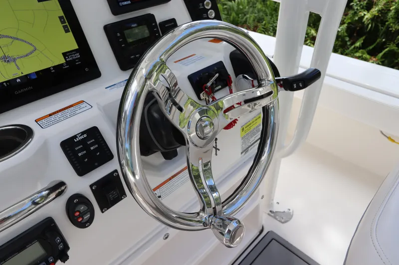Slide: The Image of 2021 Robalo 246 Cayman SD helm with chrome steering wheel and navigation controls. - 24