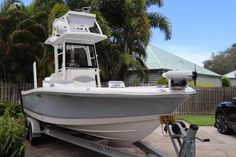 Slide: The Image of 2021 Robalo 246 Cayman SD boat on trailer, parked in a driveway with tropical background. - 3
