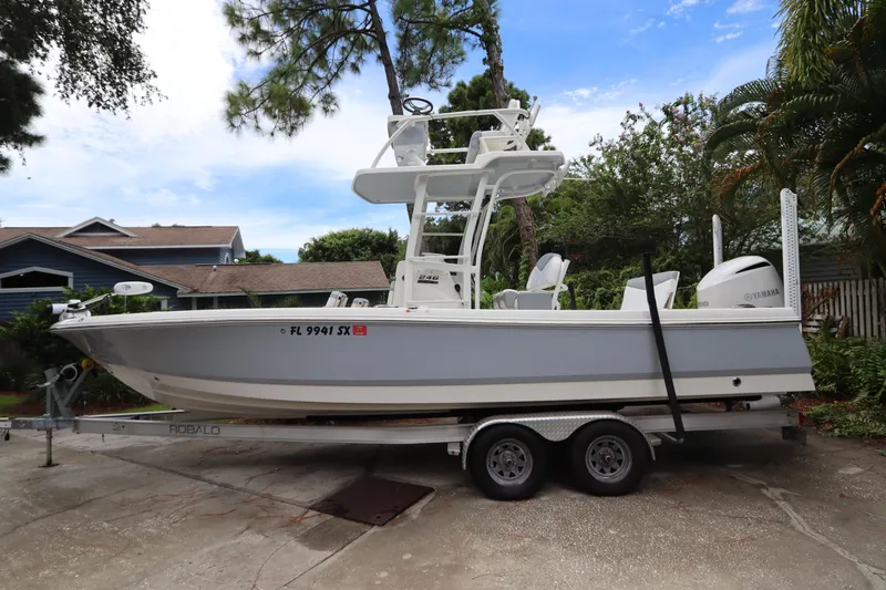 Slide: The Image of 2021 Robalo 246 Cayman SD boat on a trailer in a residential driveway. - 4