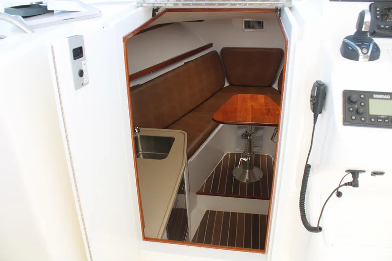 Slide: The Image of 2021 Albemarle 30 Express cabin interior with brown seating, wooden table, and navigation equipment. - 26