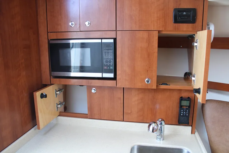 Slide: The Image of 2021 Albemarle 30 Express boat interior with microwave, wooden cabinets, and sink. - 29