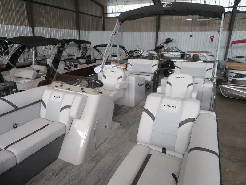 Slide: The Image of 2024 Crest Classic LX 220 SLRC pontoon boat with luxurious seating in a showroom. - 11