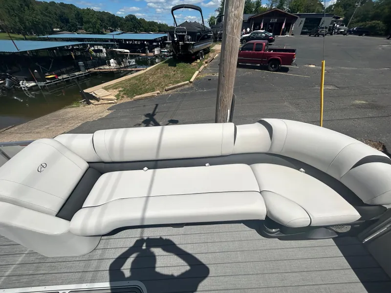 Slide: The Image of 2023 Avalon 2785 ENT FS boat with white cushioned seating at a marina. - 10