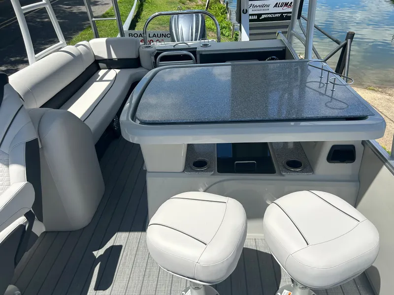 Slide: The Image of 2023 Avalon 2785 ENT FS boat interior with seating and table near the water. - 18