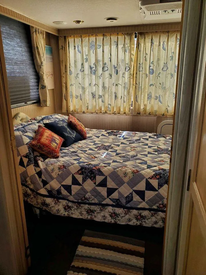 Slide: The Image of Cozy bedroom in a 1999 Gibson Sport, featuring a quilted bedspread and floral curtains. - 2