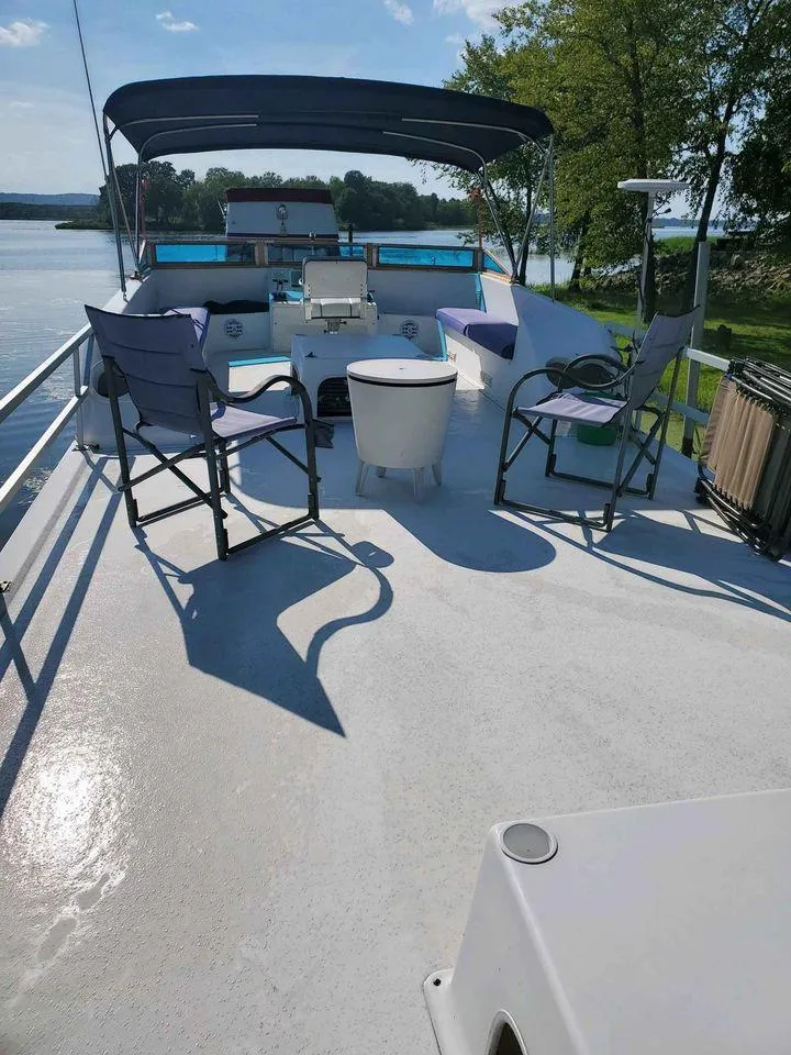 Slide: The Image of 1999 Gibson Sport boat deck with chairs and table, set against a scenic lake backdrop. - 6