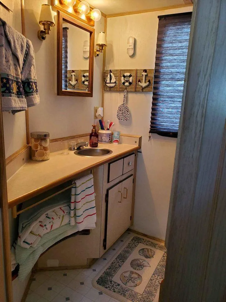 Slide: The Image of Cozy bathroom in a 1999 Gibson Sport, featuring nautical decor and warm lighting. - 7