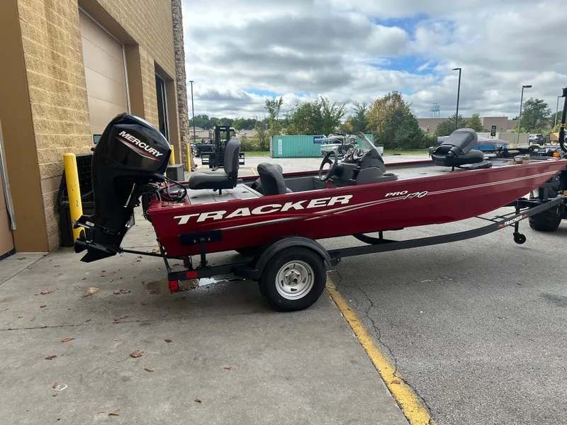Slide: The Image of 2024 Tracker Pro 170 boat with Mercury engine parked outside a building. - 2