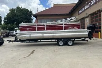 Slide: The Image of 2024 Sun Tracker Party Barge 22 RF DLX pontoon boat parked outside a boat center. - 2