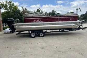 The Image of 2024 Sun Tracker Party Barge 22 RF DLX pontoon boat on trailer, parked outdoors. - 0