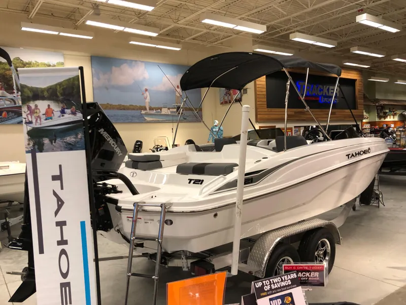 Slide: The Image of 2024 Tahoe T21 boat on display in showroom with promotional banners. - 2