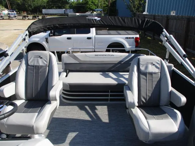 Slide: The Image of 2024 Bennington 22SXSB pontoon boat interior with gray seating and a white truck in the background. - 3