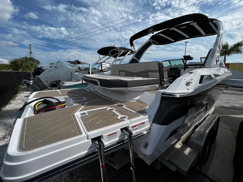 Slide: The Image of 2024 Monterey 275SS boat with swim platform and seating, docked under a partly cloudy sky. - 3