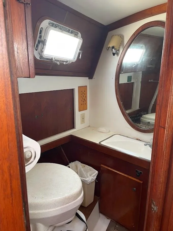 Slide: The Image of 1977 Gulfstar 37 yacht bathroom with wooden cabinetry, oval mirror, and porthole window. - 11