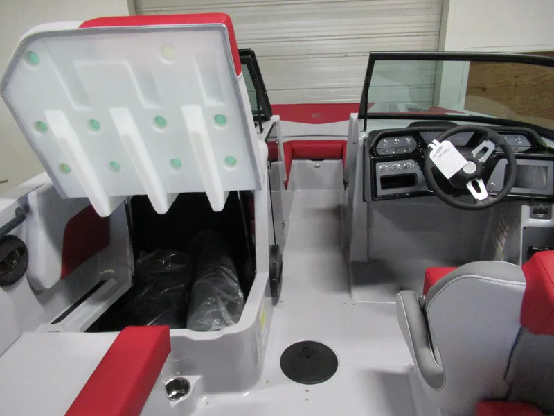 Slide: The Image of 2024 MasterCraft NXT 22 boat interior with red and white seating, open storage compartment, and steering console. - 8