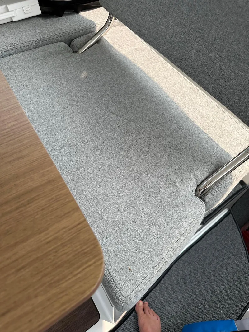 Slide: The Image of Interior seating of 2020 Beneteau Antares 8 OB boat with gray cushions and wooden table. - 10