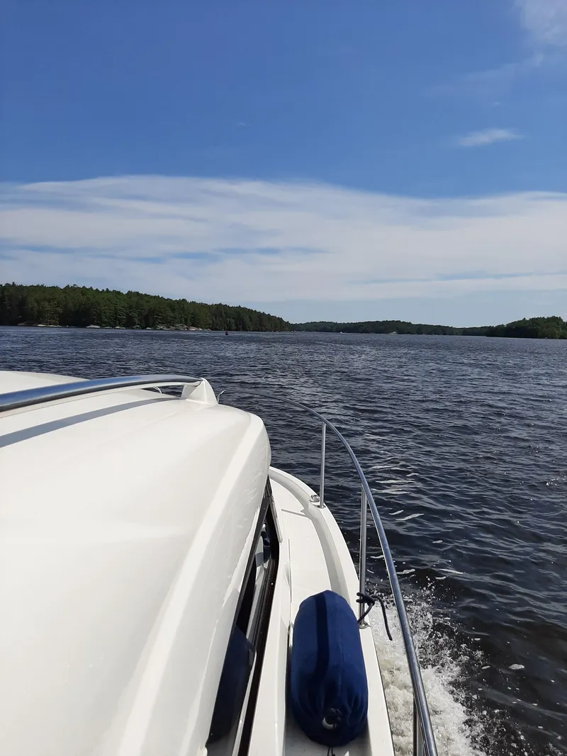 Slide: The Image of Beneteau Antares 8 OB 2020 cruising on a serene lake under a clear blue sky. - 2