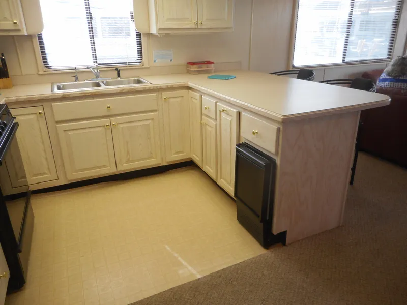 Slide: The Image of 1995 Stardust Cruisers The Verdict houseboat kitchen with L-shaped counter and wooden cabinets. - 29