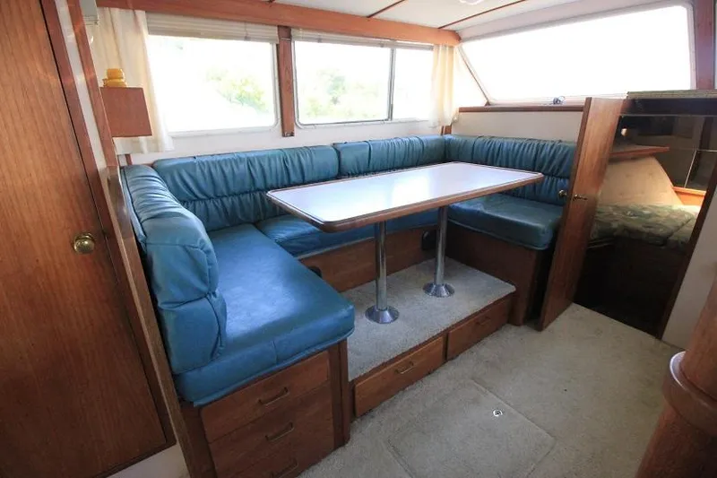 Slide: The Image of 1989 Tollycraft 30 Sport Cruiser interior dining area with blue cushioned seating and wooden table. - 14