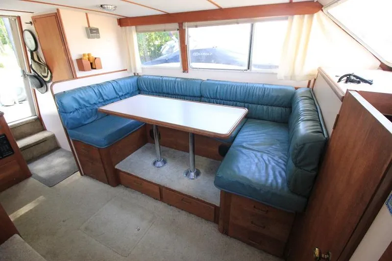 Slide: The Image of 1989 Tollycraft 30 Sport Cruiser interior dining area with blue cushioned seating. - 15
