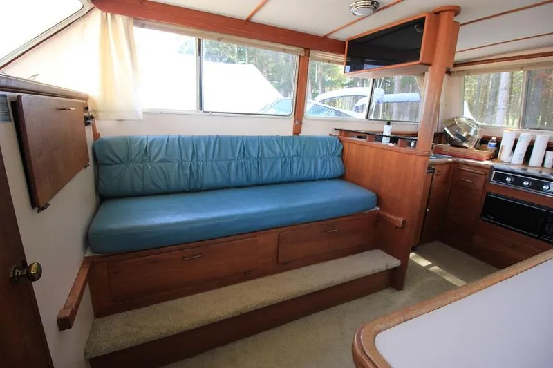 Slide: The Image of Interior of 1989 Tollycraft 30 Sport Cruiser with blue cushioned seating and wooden cabinetry. - 16